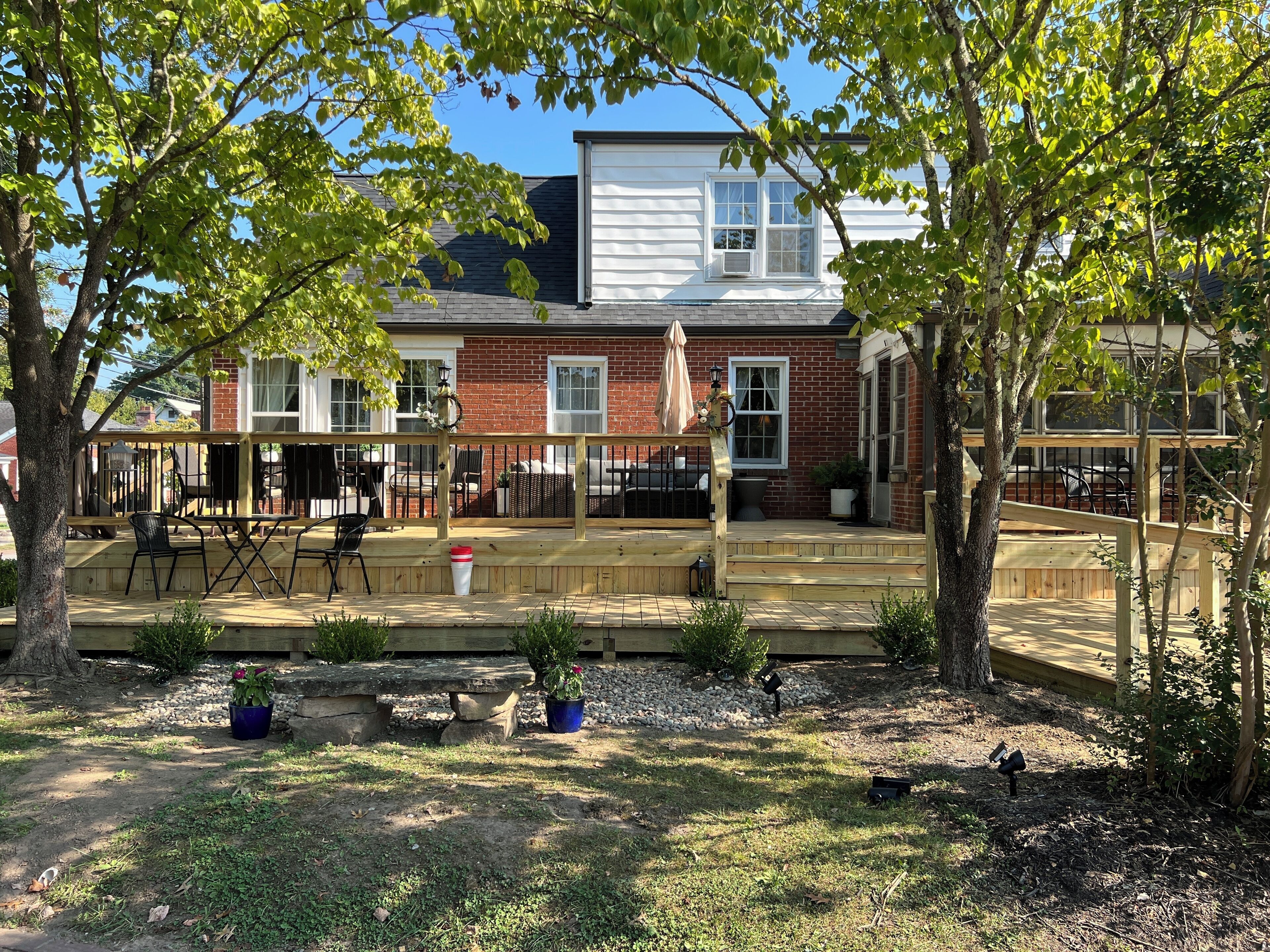 A two-story house with a covered patio, outdoor seating, and a brick exterior.