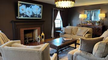 A living room with a fireplace, a chandelier, and a large painting of flowers.