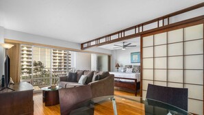 Una sala moderna con una mesa de centro de vidrio, un sofá y una cama con cabecera de madera.