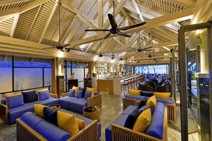 A spacious indoor area with multiple seating arrangements, a bar area, and a high ceiling with fans. - Layana Resort & Spa (Koh Lanta)