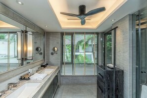A modern bathroom with a ceiling fan, large mirrors, and a view of greenery outside. - Layana Resort & Spa (Koh Lanta)