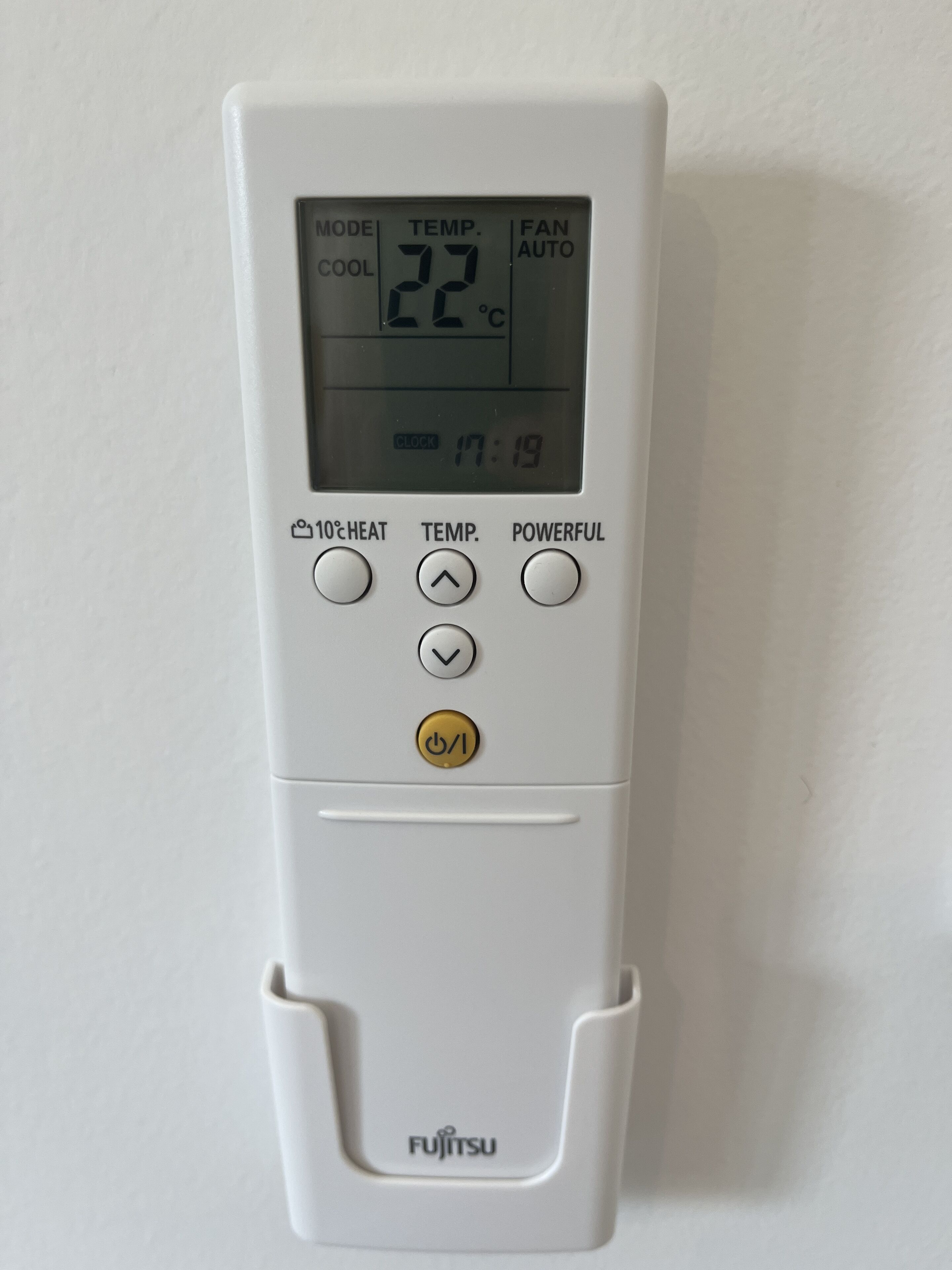 Eine weiße Fujitsu-Klimaanlage mit digitaler Anzeige, die 22°C, eine Uhr und Bedienelemente für Modus, Temperatur und Lüftereinstellungen zeigt.