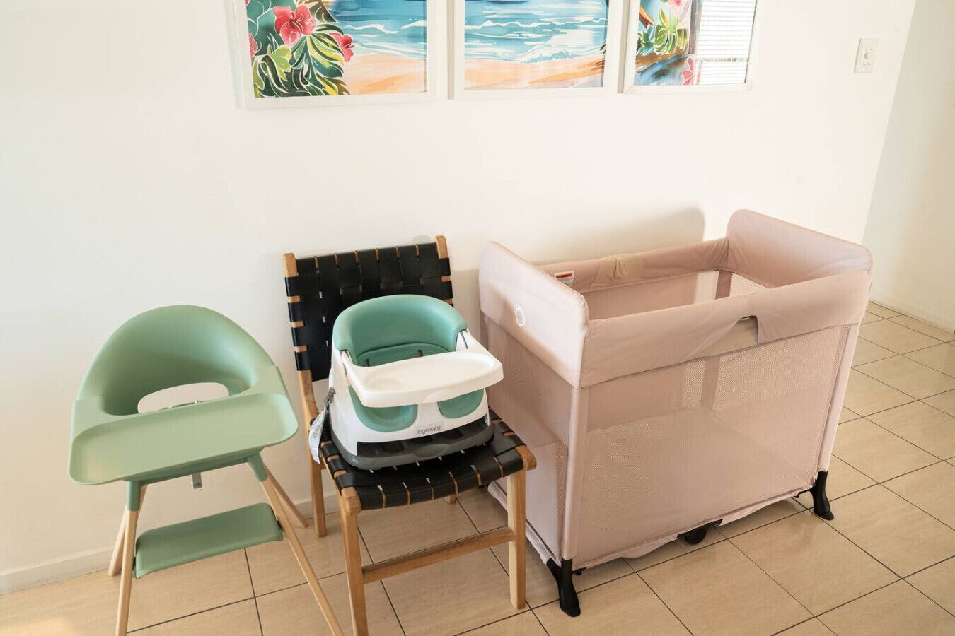 A room with a green chair, a teal baby seat, and a pink changing table.