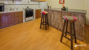 A kitchen with wooden cabinets, a stove, and two stools.