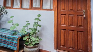 A wooden door with a sign reading "Pumpkin," a window with curtains, a potted plant, and a small table with a patterned cloth.