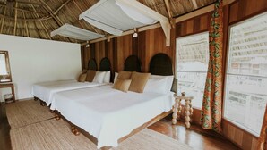 Een kamer met een groot bed, houten wanden en een rieten dak.