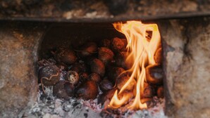 Een stenen oven met vuur erin, waarin verschillende ronde objecten liggen.