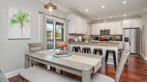 Una cocina moderna con armarios blancos, una isla central y un comedor con banco.