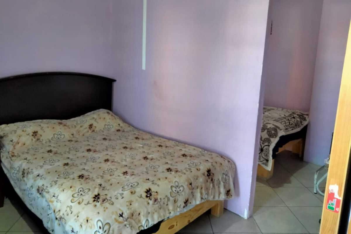 A bedroom with a single bed, a wooden headboard, and a small table with a patterned tablecloth.