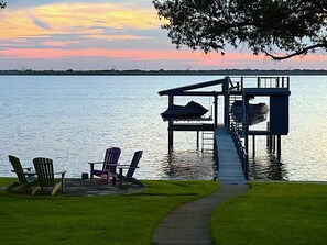 A dock extending into a calm lake with chairs and a table on the dock, surrounded by grassy areas. - Waterfront 3-bedroom house on Cedar Creek Lake in Star Harbor, dock and porch
  (Malakoff)