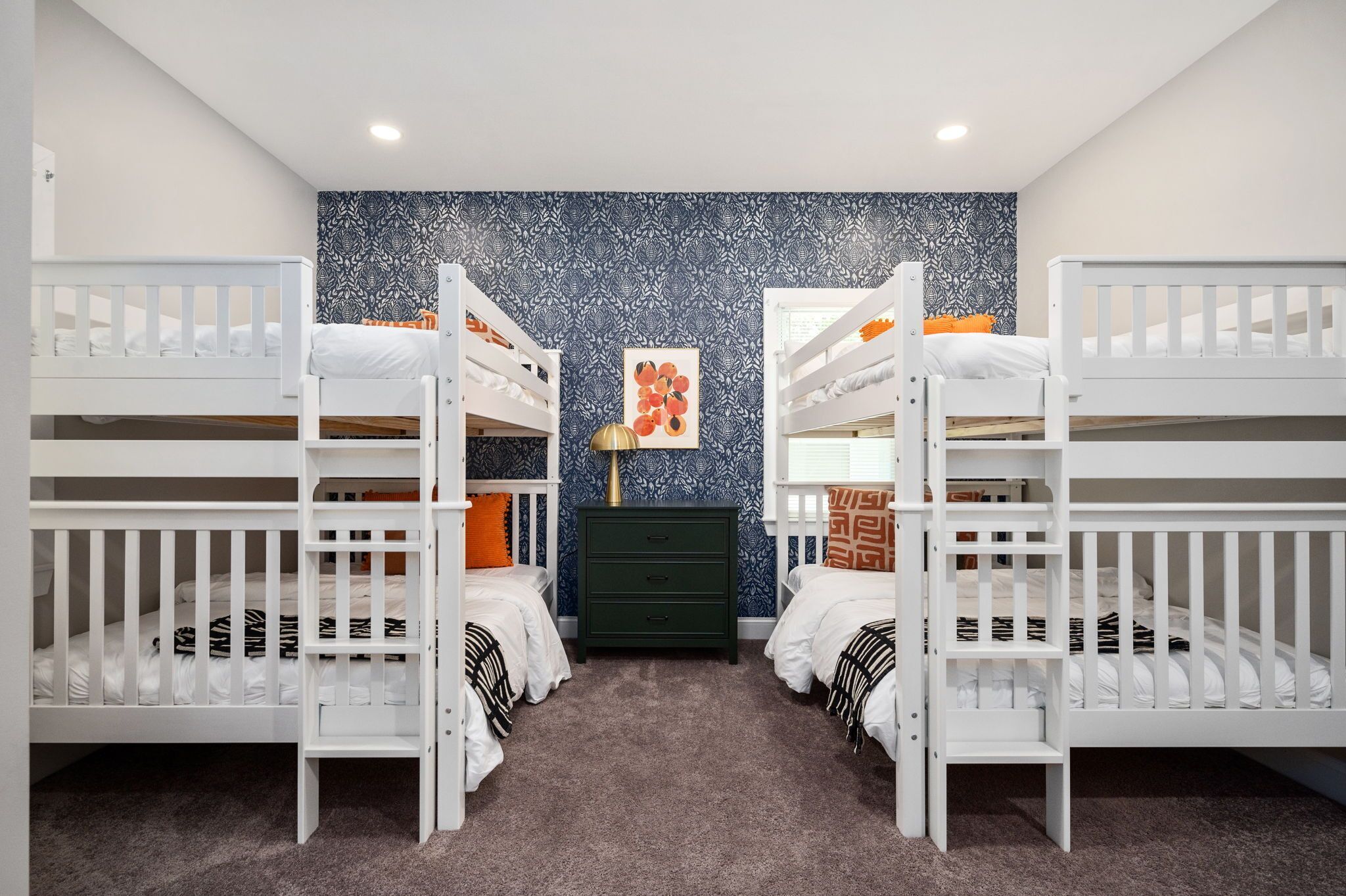 A children's room with bunk beds, a dresser, and a wall with a floral pattern.