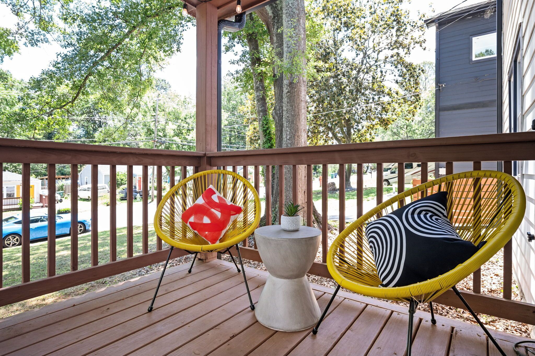 A wooden deck with two yellow wicker chairs and a small table.
