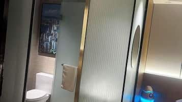 A bathroom with a toilet, a towel hanging on the wall, and a nightstand with a blue device.