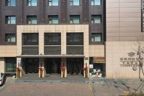 A hotel entrance with a modern facade, a covered entrance area, and a sign indicating the hotel's name. - Yatai Longda Hotel (Changchun)