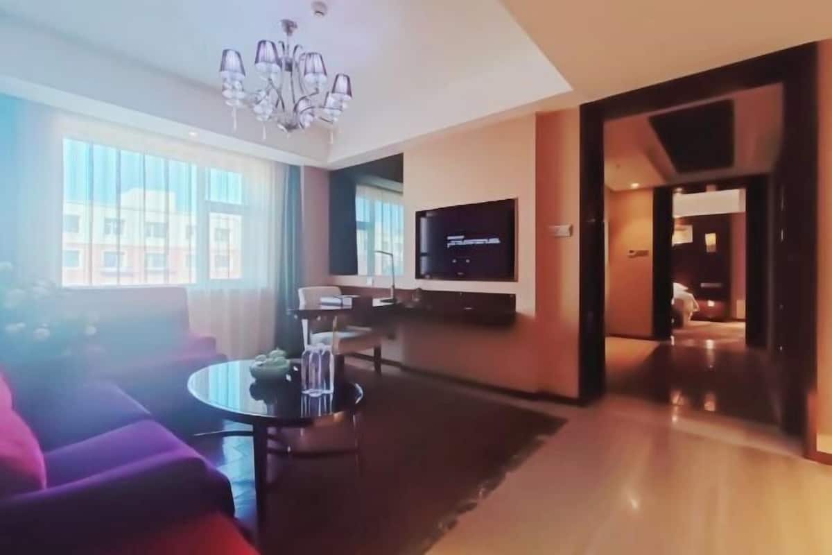 Una sala de estar moderna con un sofá, una mesa de centro, un televisor y una araña.