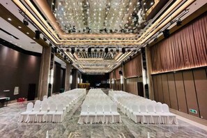 A long banquet table with rows of white chairs, a chandelier, and a marble floor. - Yatai Longda Hotel (Changchun)
