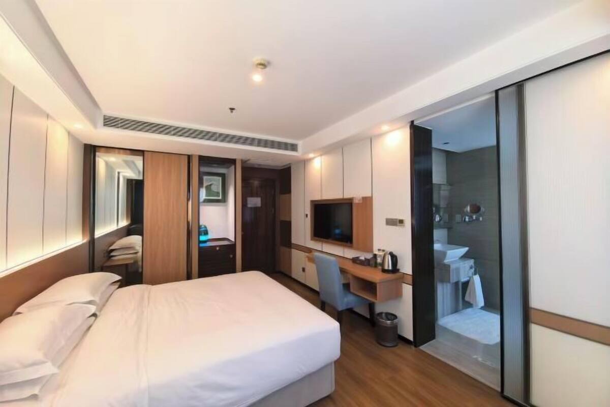 Una habitación de hotel con cama, escritorio, televisión y baño.