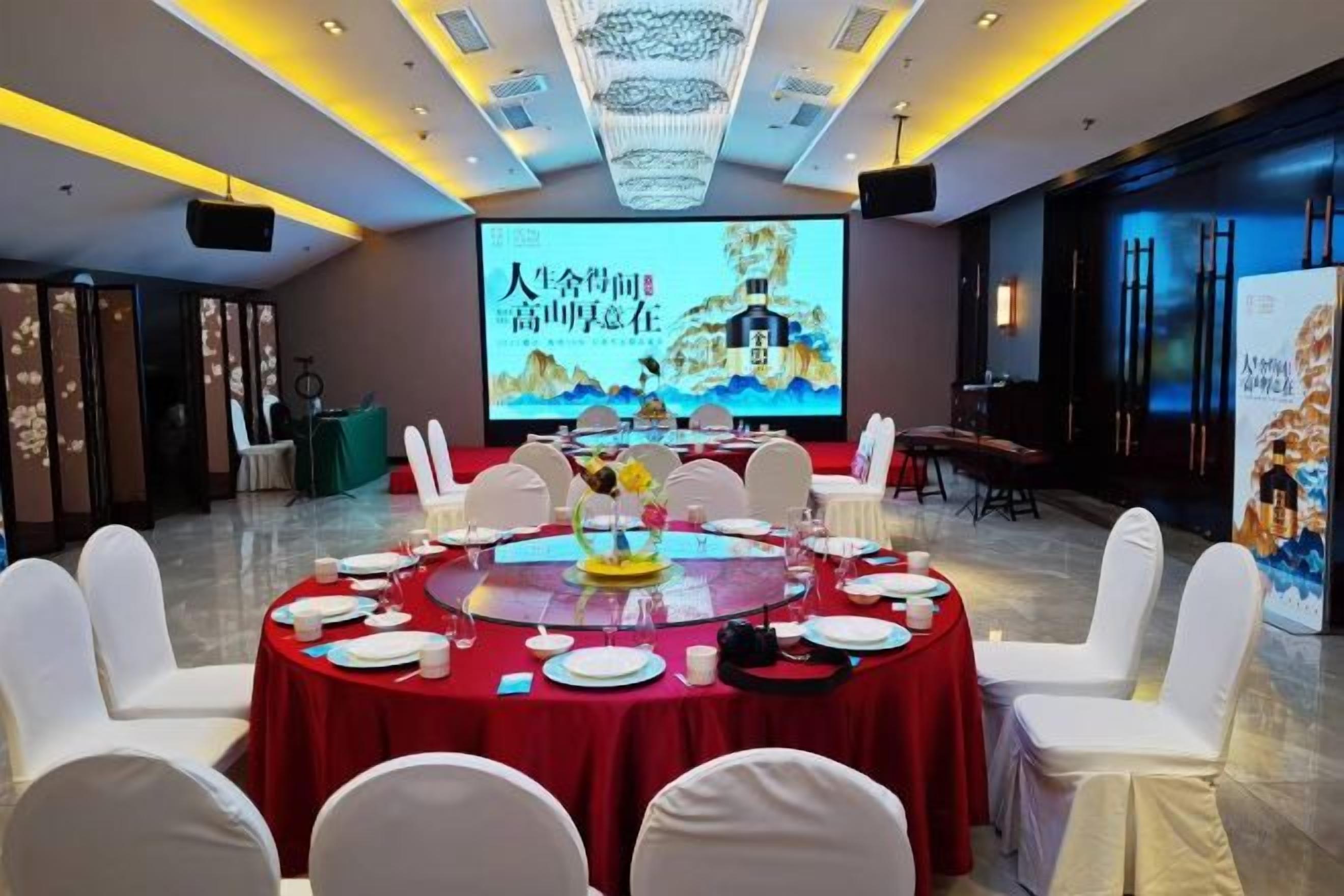 A conference room with a round table, white chairs, and a large screen displaying a presentation.