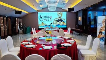 A conference room with a round table, white chairs, and a large screen displaying a presentation.