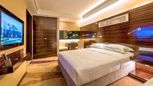 Una habitación de hotel moderna con una cama grande, televisión, escritorio y baño.