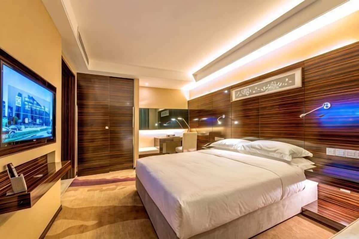 Una habitación de hotel moderna con una cama grande, televisión, escritorio y baño.