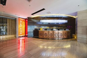 A reception area with a wooden reception desk, a large illuminated sign, and a polished floor. - Yatai Longda Hotel (Changchun)