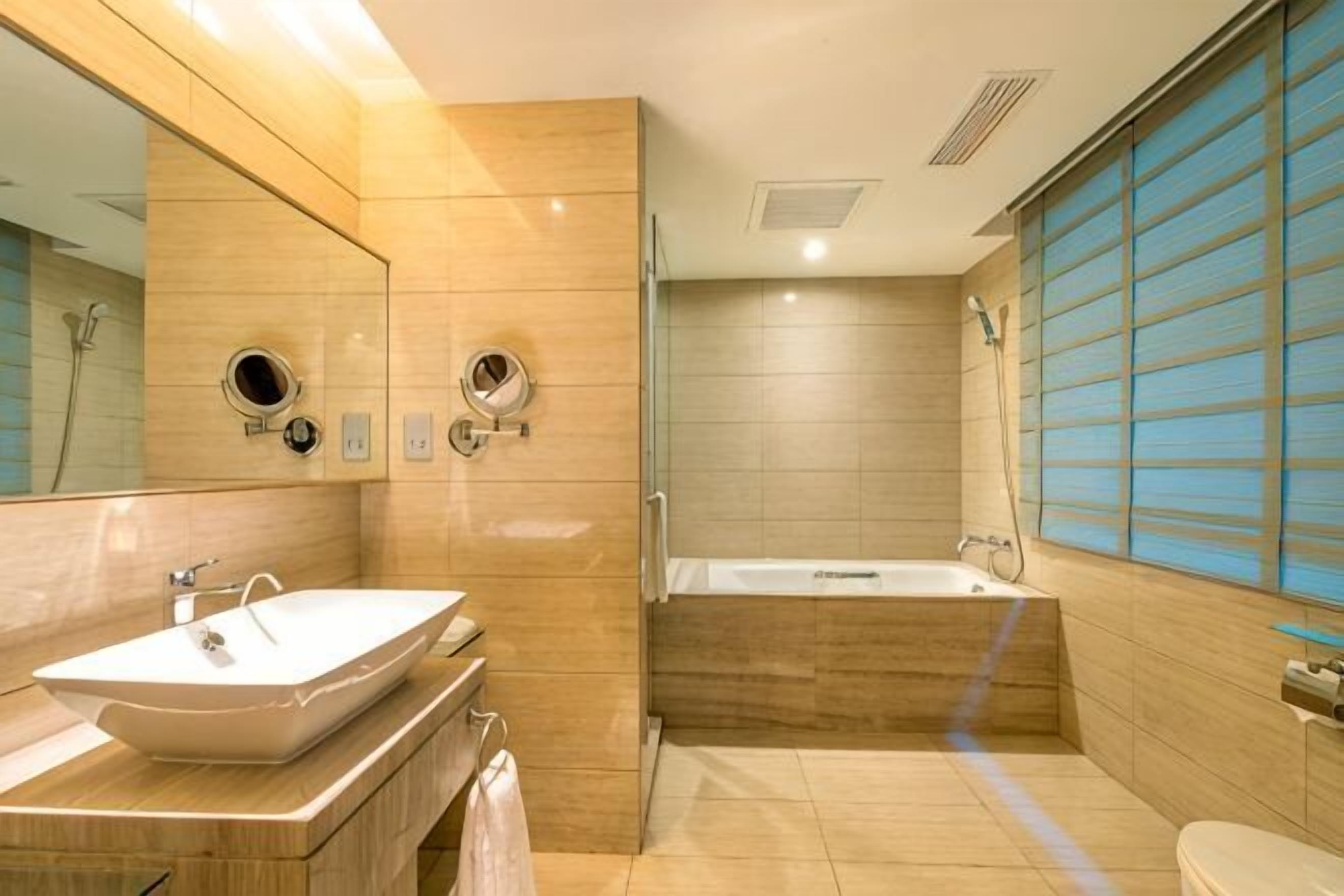 Un baño con lavabo, espejo, bañera e inodoro.