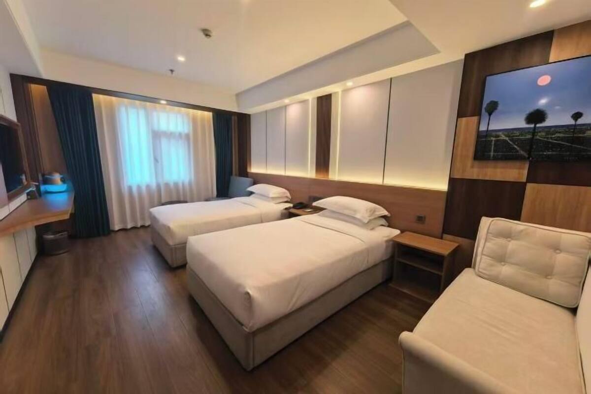 Una habitación de hotel con dos camas, un escritorio, una silla y un televisor.