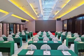 A conference room with rows of tables, chairs, and a stage. - Yatai Longda Hotel (Changchun)