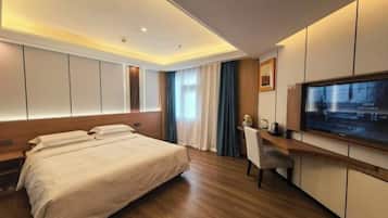 A modern hotel room with a large bed, a desk, a TV, and a window with curtains.