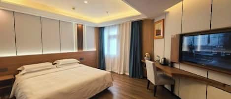 Una habitación de hotel moderna con una cama grande, un escritorio, un televisor y un ventanal con cortinas.