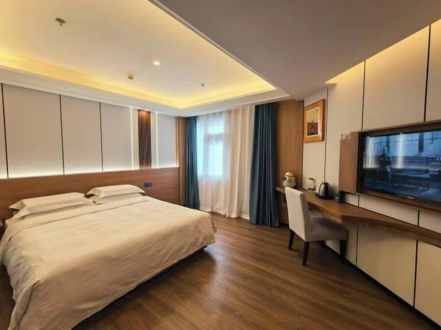 Een moderne hotelkamer met een groot bed, een bureau, een televisie en een raam met gordijnen.