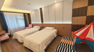 A hotel room with two beds, a wooden headboard, a striped rug, and a colorful kite decoration.