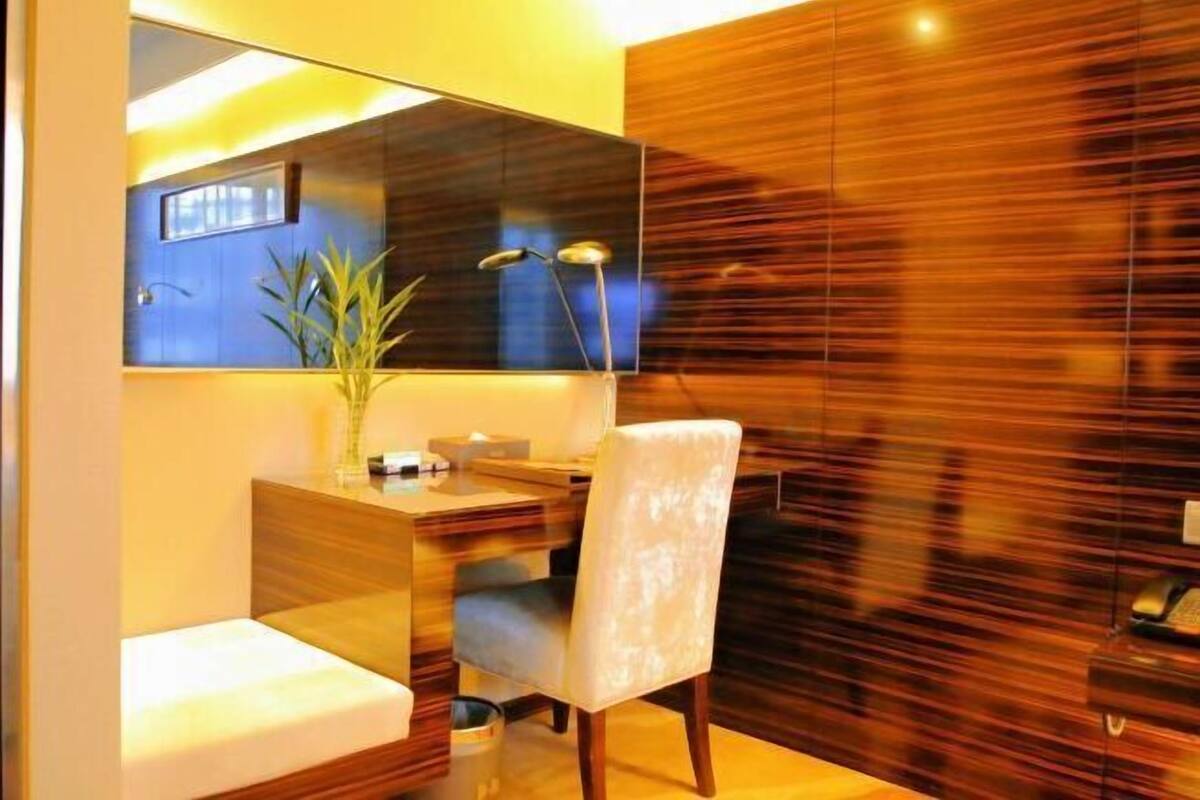 Un baño moderno con tocador de madera, un espejo, un lavamanos y una silla.
