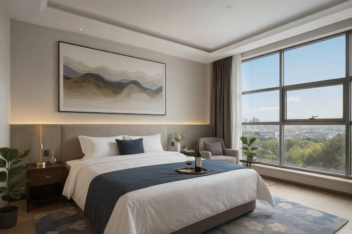 Una habitación de hotel moderna con una cama grande, vistas a la ciudad y un cuadro en la pared.