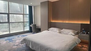 A hotel room with a large window, a bed, a chair, and a nightstand. - Huangshi Hotel (Anshun)