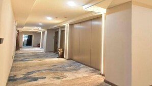 A hotel hallway with a patterned carpet, recessed lighting, and a view into another room. - Huangshi Hotel (Anshun)