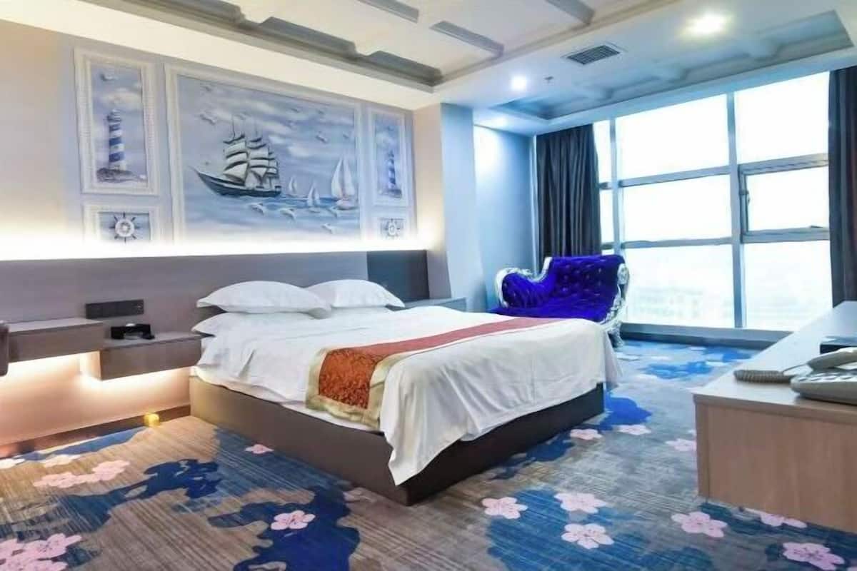 Una habitación de hotel con una cama grande, un escritorio, una silla y una ventana con cortinas.