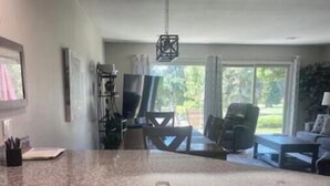 Una cocina con encimeras de granito, armarios blancos y un comedor con mesa y sillas.