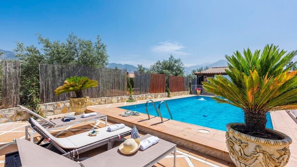 A pool area with lounge chairs and a stone wall. - La Estaquilla Dúrcal by Ruralidays (Granada)