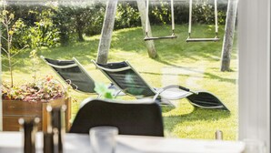 A patio area with two lounge chairs and a swing set, overlooking a grassy garden. - Lovely home in Blokhus with WiFi (Blokhus)