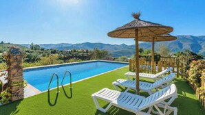 A swimming pool with a view of mountains, surrounded by white lounge chairs and a thatched umbrella. - Cortijo El Cerrillo Órgiva by Ruralidays (Granada)
