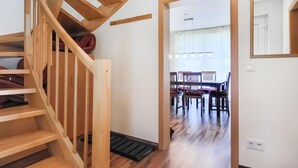 Una scala in legno conduce a una sala da pranzo con tavolo e sedie.