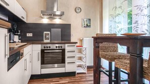 Una cucina moderna con forno a incasso, piano cottura e cappa aspirante. È presente un'area pranzo con tavolo e sedie.