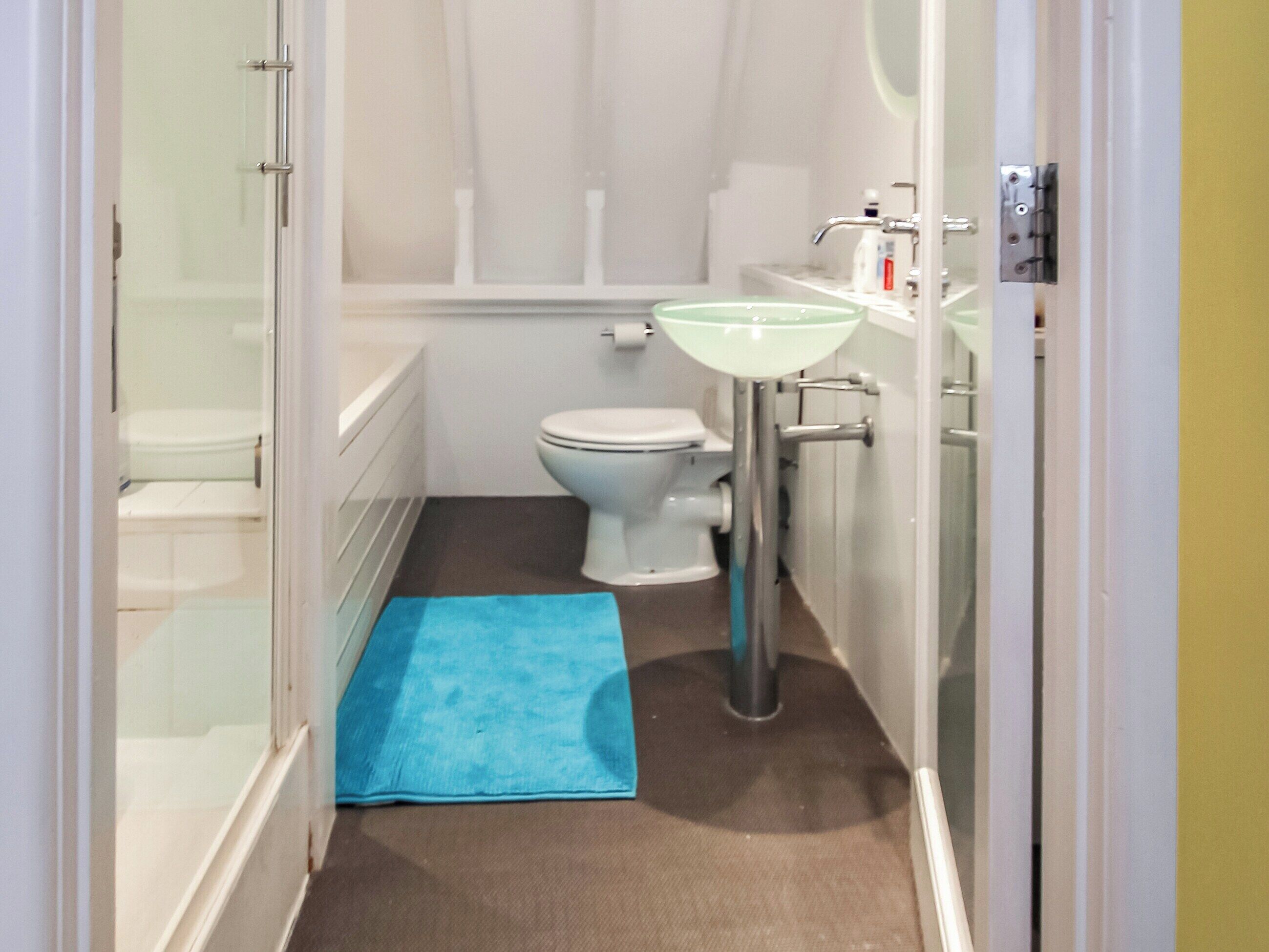 A small, compact bathroom with a toilet, sink, and shower area.