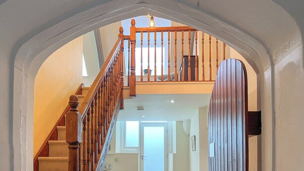 Una escalera con barandillas de madera que lleva a un rellano en el segundo piso.