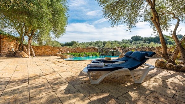 A poolside area with lounge chairs and a stone wall.