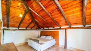 A bedroom with a wooden ceiling, a bed, and a bedside table. - Vila do Frade (Alexânia)