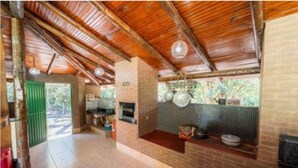 A kitchen with a brick wall, wooden ceiling, and hanging pots. - Vila do Frade (Alexânia)