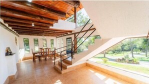 A spacious room with a high ceiling, a staircase leading to an upper level, and a large window offering a view of the outdoors. - Vila do Frade (Alexânia)